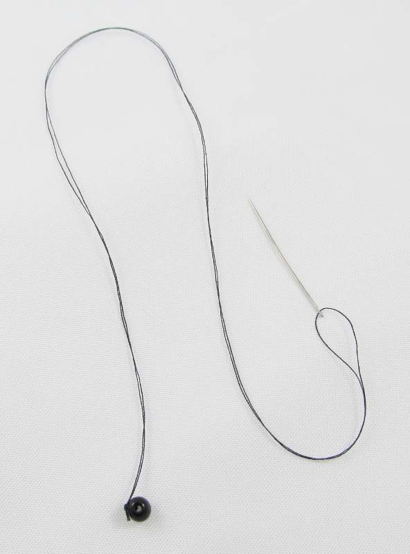 For eyes, tie a black bead onto thread. Push the needle through the eye position on the face to the back of the head. Tie off the thread and cover the knot with loose wool.