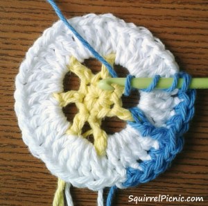 Wrap the yarn around your hook 2 times. Insert your hook under the yellow ch-2 post from right to left. Pull up a loop so that your hook looks like the photo above. Yarn over once and pull through the first 2 loops on your hook. Yarn over again and pull through the next 2 loops. Yarn over again and pull through the last 2 loops on your hook.